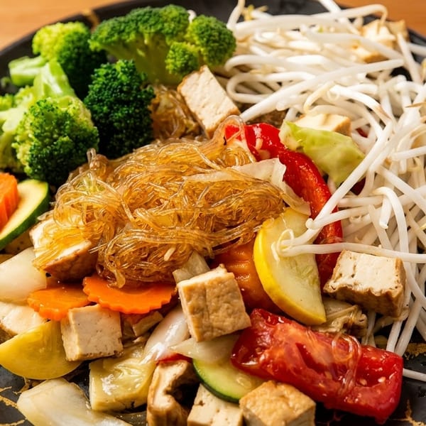 A colorful vegan stir-fry with glass noodles, broccoli, bean sprouts, tofu, and mixed vegetables.