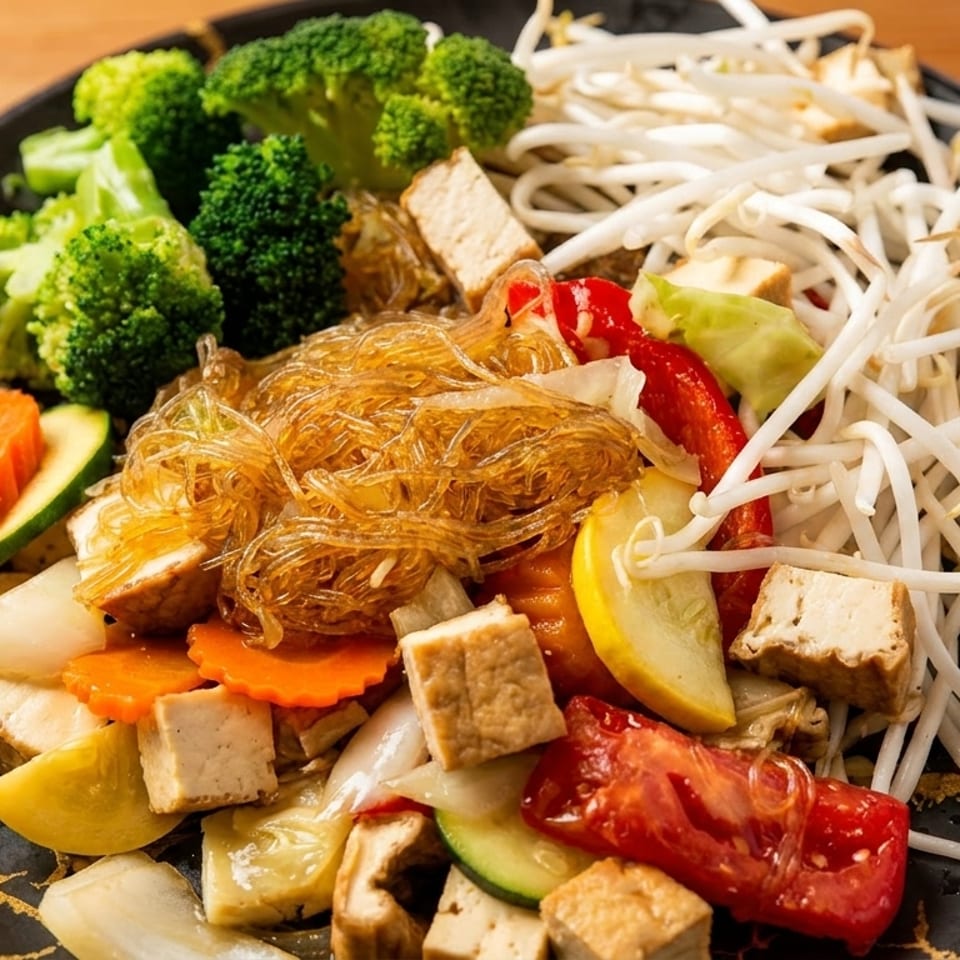 A colorful vegan stir-fry with glass noodles, broccoli, bean sprouts, tofu, and mixed vegetables.