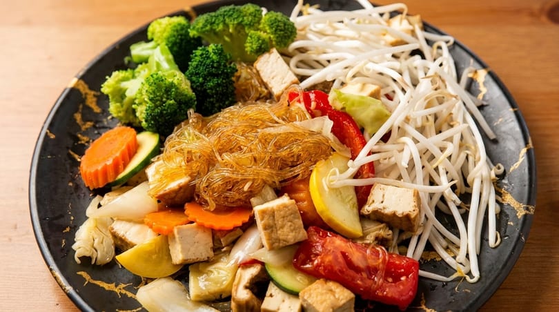 A colorful vegan stir-fry with glass noodles, broccoli, bean sprouts, tofu, and mixed vegetables.
